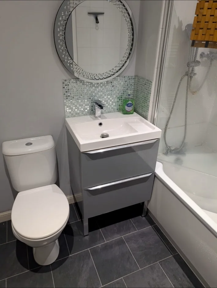 Compact completed bathroom with vanity, toilet and bath